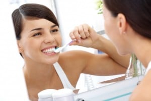 Woman brushing teeth in mirror 